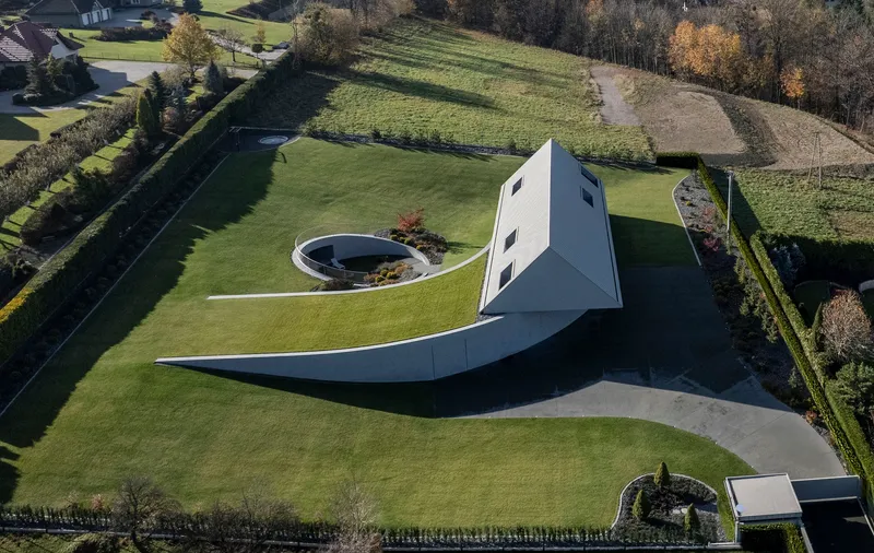Aerial view of the white gabled volume with curved wing walls extending into the lawn