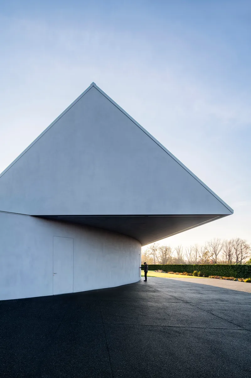 Triangular gable end with recessed entry and cantilevered overhang at dusk