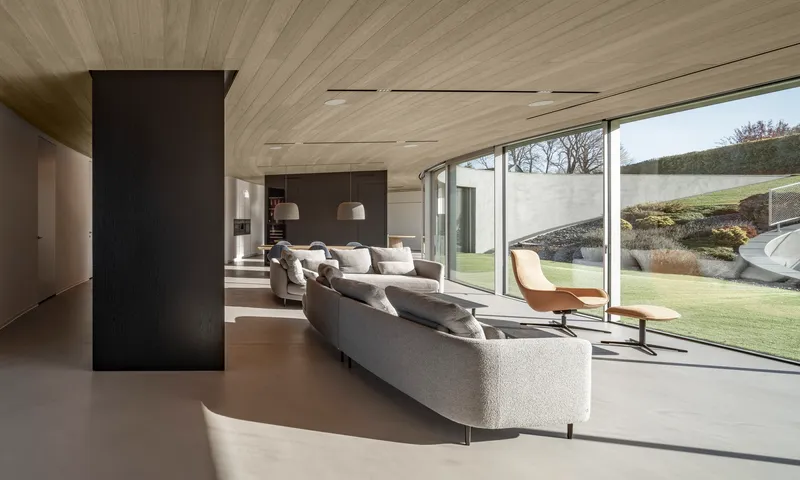 Open living space with timber ceiling planks and floor-to-ceiling glazing overlooking the garden