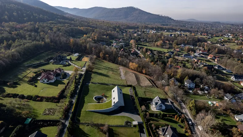 Drone view of the residence set among fields and forested hills at dawn