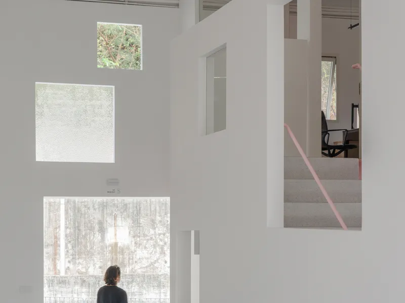 Person standing before three vertically stacked windows with translucent and clear glass overlooking winter trees