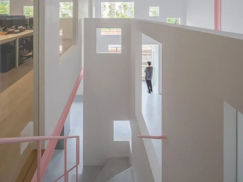 Multi-level interior with a lone figure standing in a doorway framed by tall white partitions