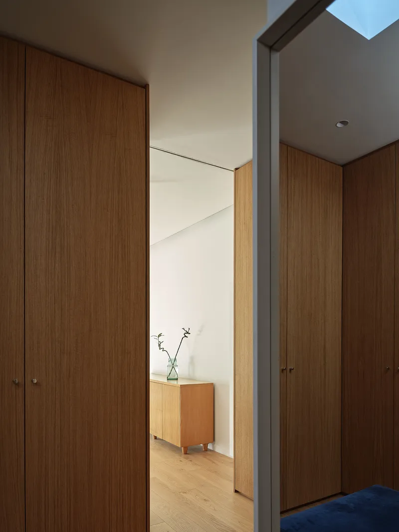 Timber-clad corridor with steel beam framing view through to hallway with oak flooring