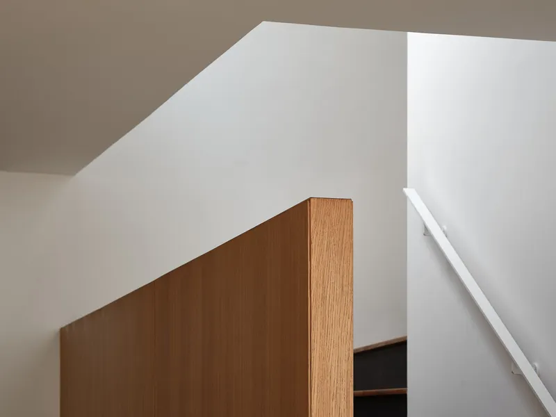 Oak-clad cabinet edge meeting white walls and ceiling in soft natural light