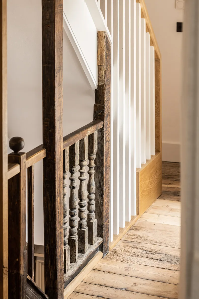 Staircase with exposed timber posts and turned wooden balustrades alongside vertical white slat partition