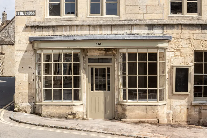 Stone facade with curved bay windows flanking a central doorway beneath zinc coping in daylight