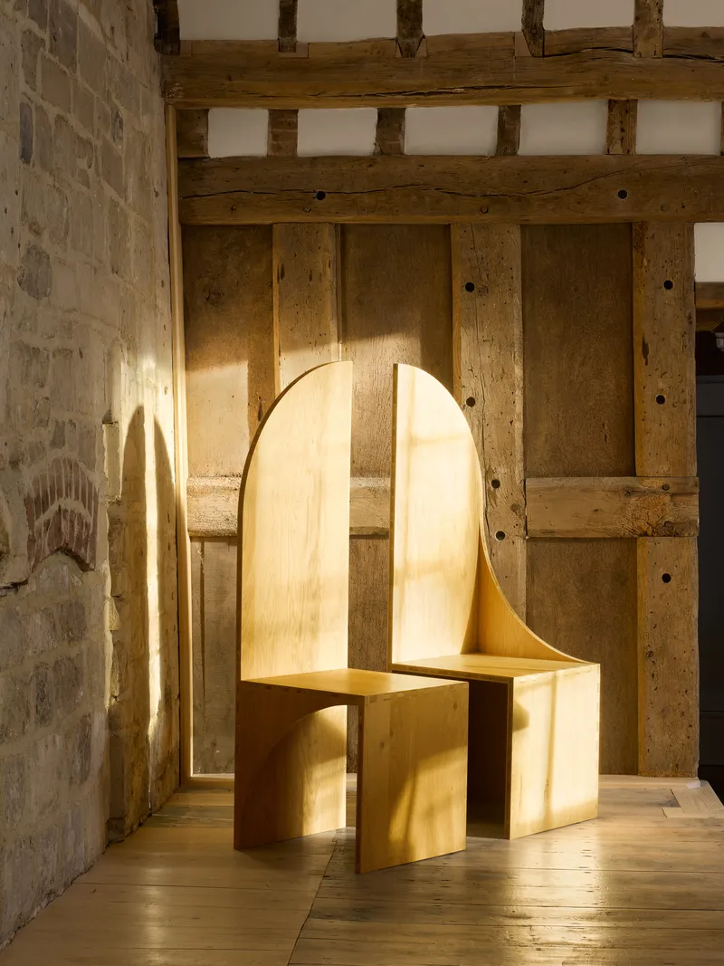 Curved plywood bench against reclaimed timber paneling in afternoon sunlight