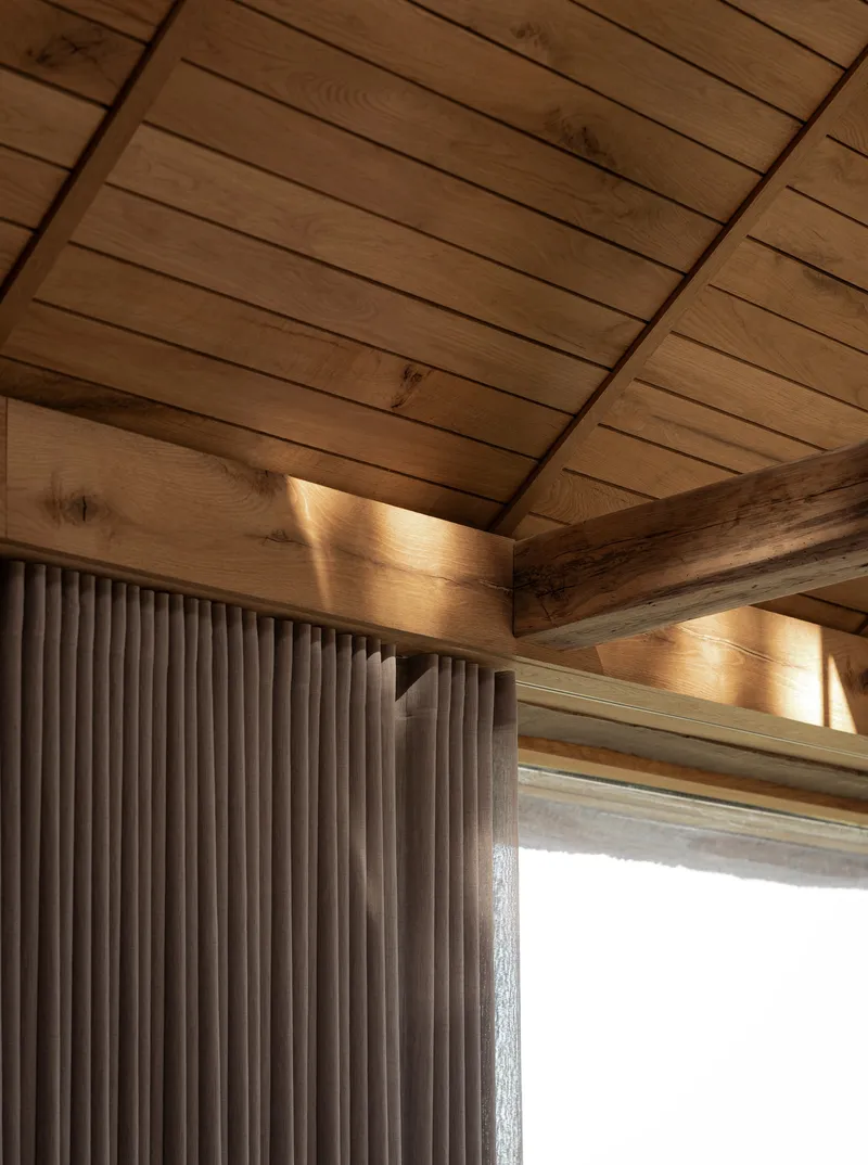 Interior corner showing timber ceiling beams and vertical fluted wall cladding with natural light
