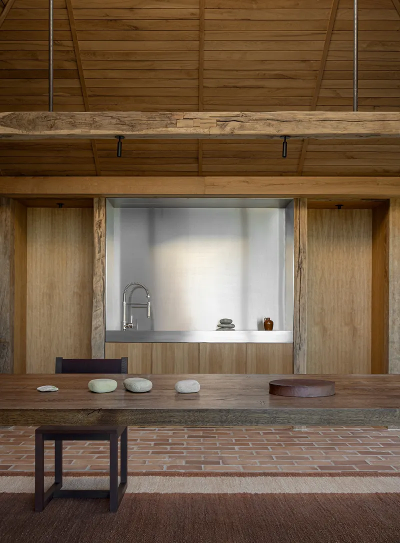 Kitchen pass-through with stainless counter set into timber wall above brick floor
