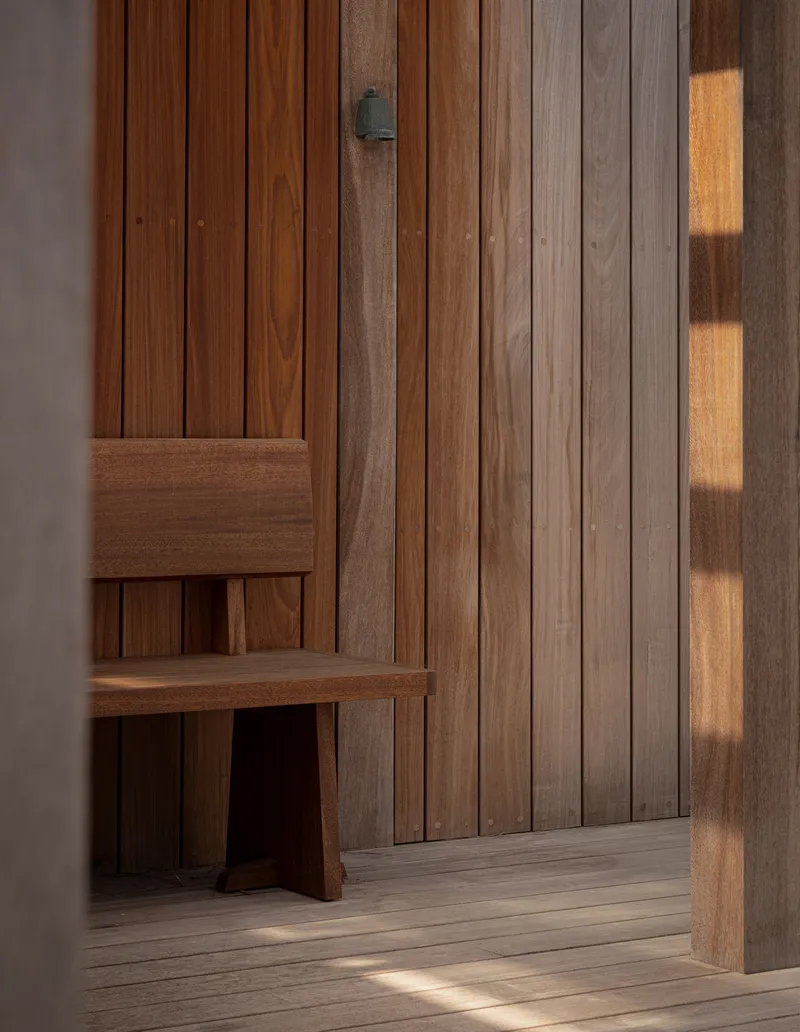 Interior timber wall cladding with a built-in bench illuminated by late afternoon sunlight