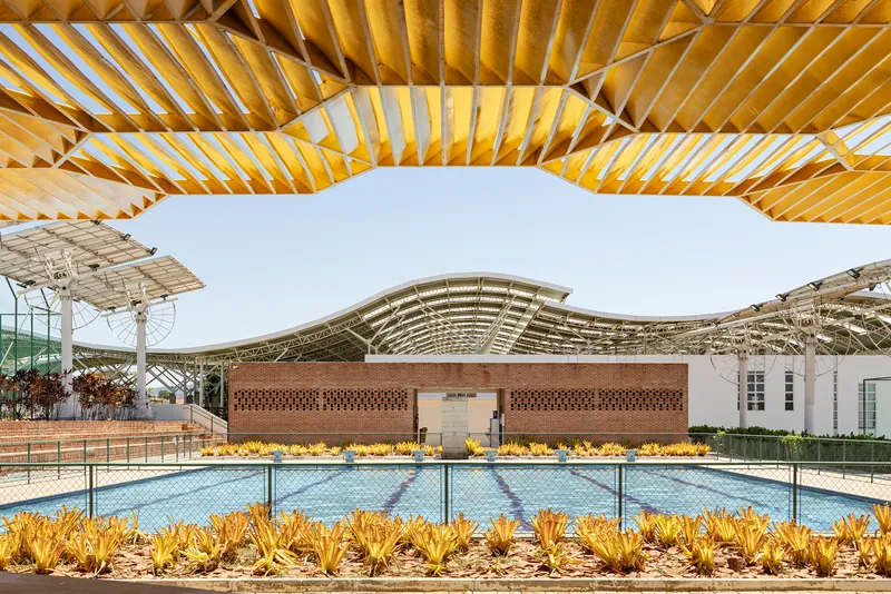 Outdoor swimming pool framed by timber pergola with yellow slatted canopy and agave plantings