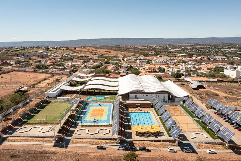 Aerial view of the sports complex with curved roofs and solar panel arrays in the arid landscape