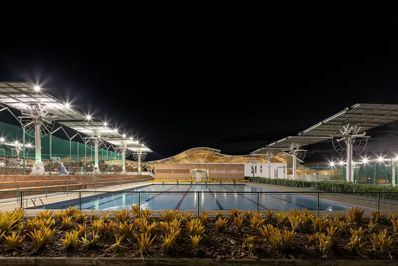 Night view of the reflecting pool with illuminated solar panel canopies and latticed central pavilion