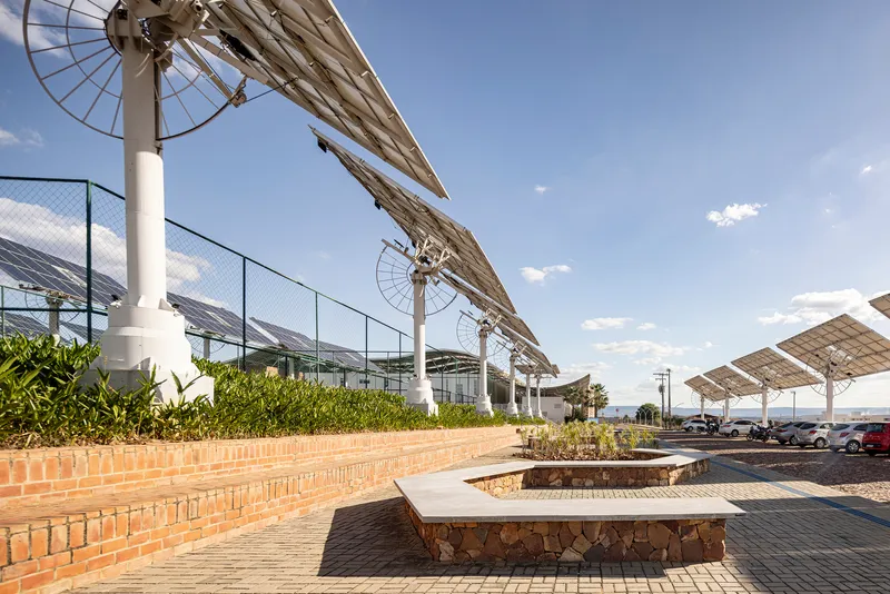 Stone bench beside brick planters and angled solar panel canopy with white support columns