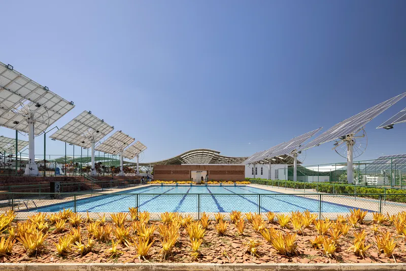 View across the lap pool toward the latticed pavilion with planted beds of yellow flowering succulents