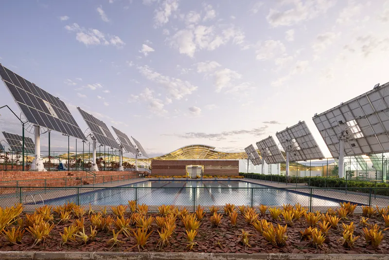 Lap pool at dusk framed by solar arrays and planted bed with latticed roof structure beyond