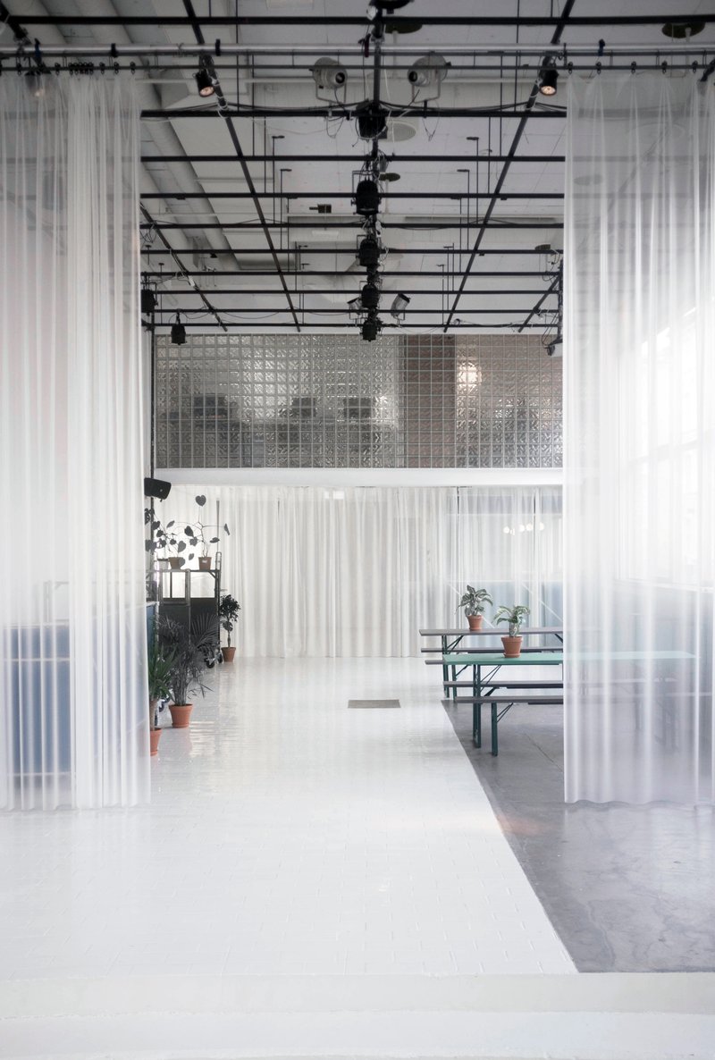 Corridor with translucent fabric partitions hanging from the industrial ceiling structure and lighting rig