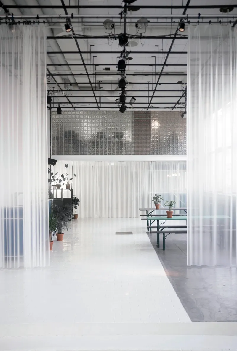 Corridor with translucent fabric partitions hanging from the industrial ceiling structure and lighting rig