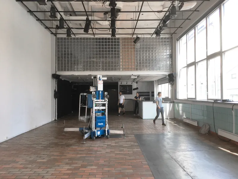 Double-height workspace with gridded glass mezzanine guardrail and exposed ceiling track lighting