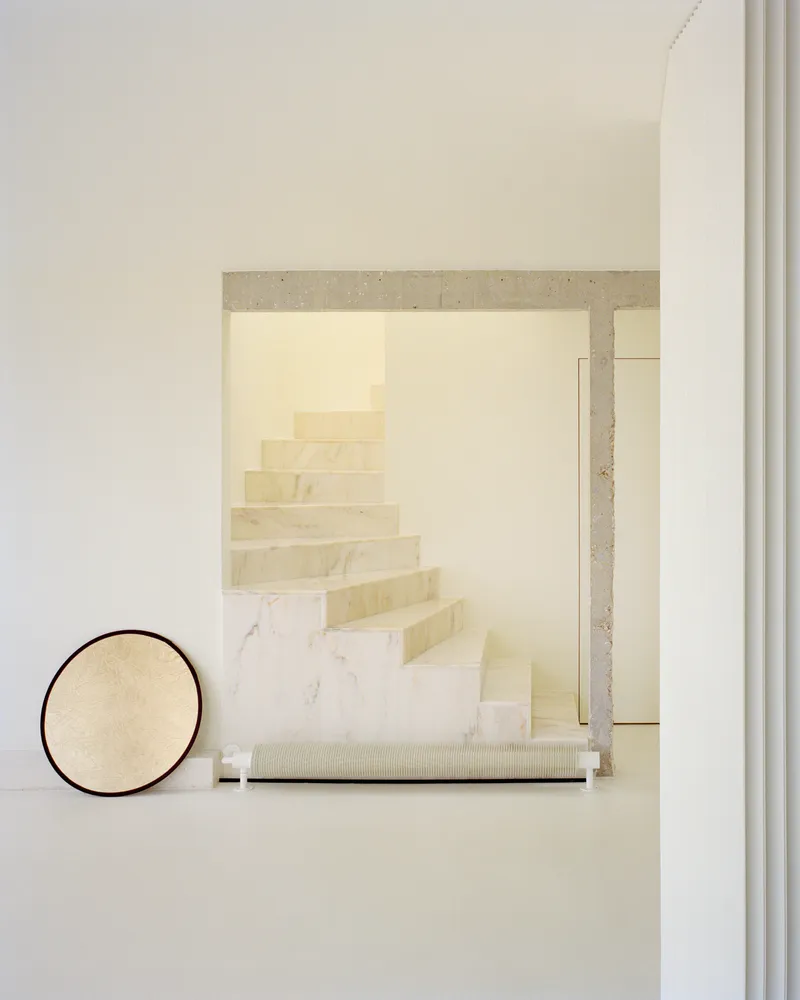 View toward stairwell through concrete portal with round mirror leaning against wall