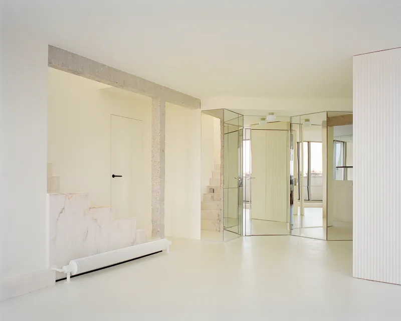 Open interior with terrazzo columns framing mirrored glass partitions and a marble-clad bench