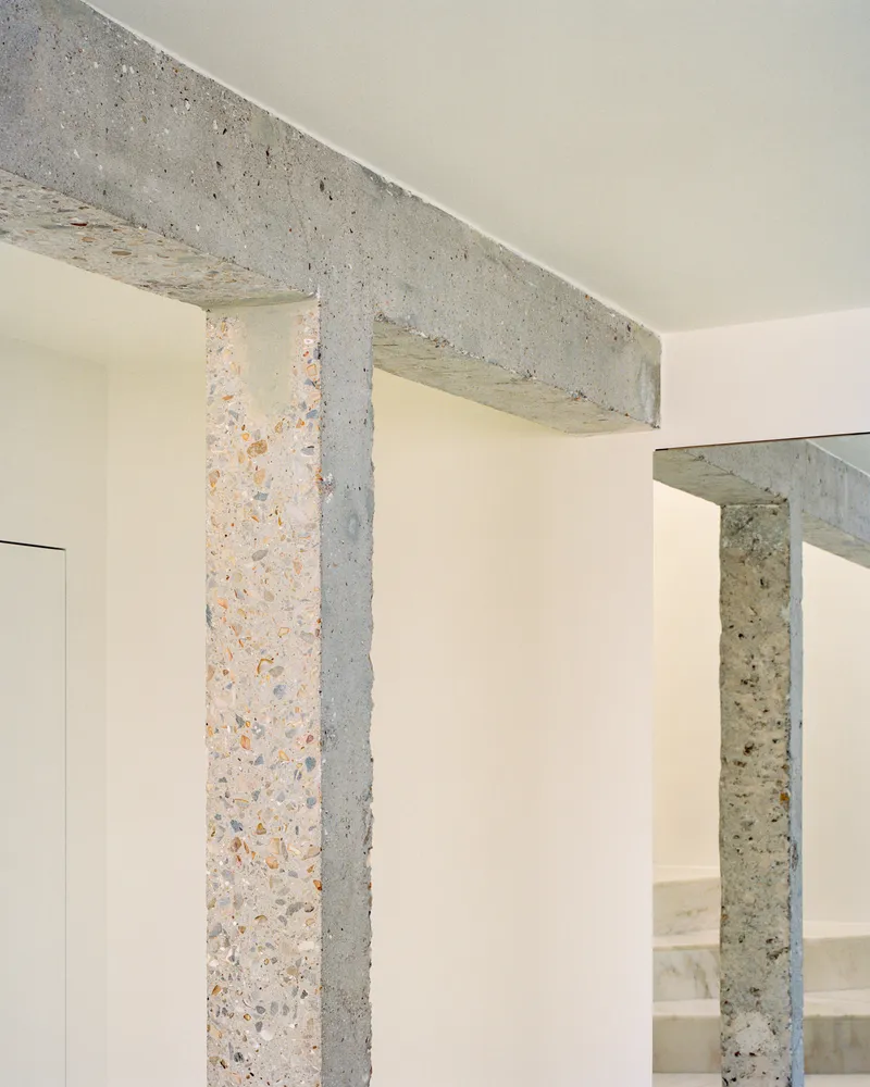 Terrazzo columns and beam junction showing aggregate texture against pale painted walls