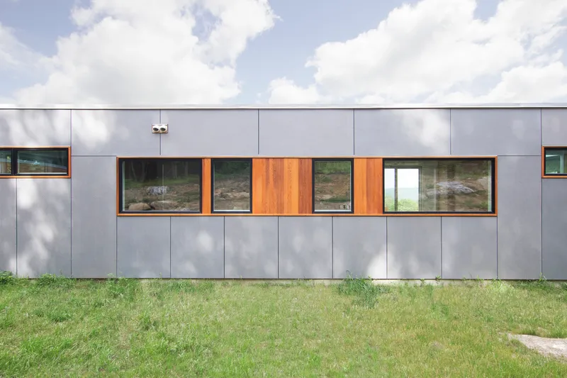 Rear elevation with gray panel cladding and timber window frames in a mowed lawn