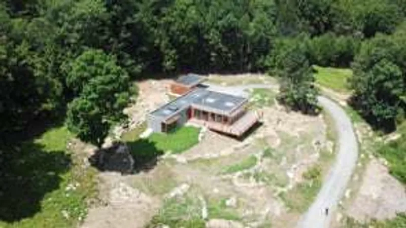 Aerial view of the residence on a rocky clearing surrounded by dense forest canopy