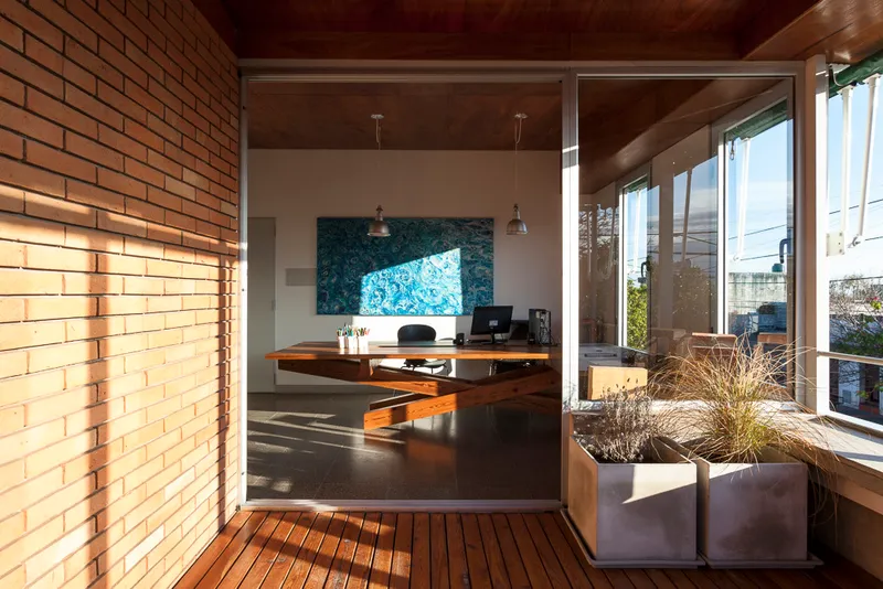 Kitchen with exposed brick wall, pendant lights, and timber deck terrace with planters visible through glass doors