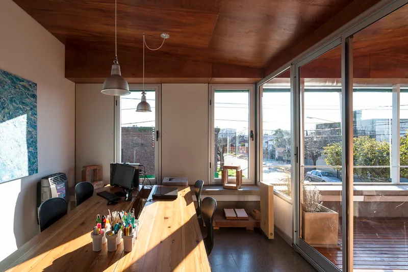 Office workspace with timber ceiling and glazed doors opening to a timber deck in afternoon light