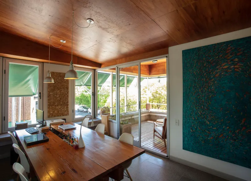 Dining area with angled timber ceiling and sliding glass doors to exterior terrace under bright daylight