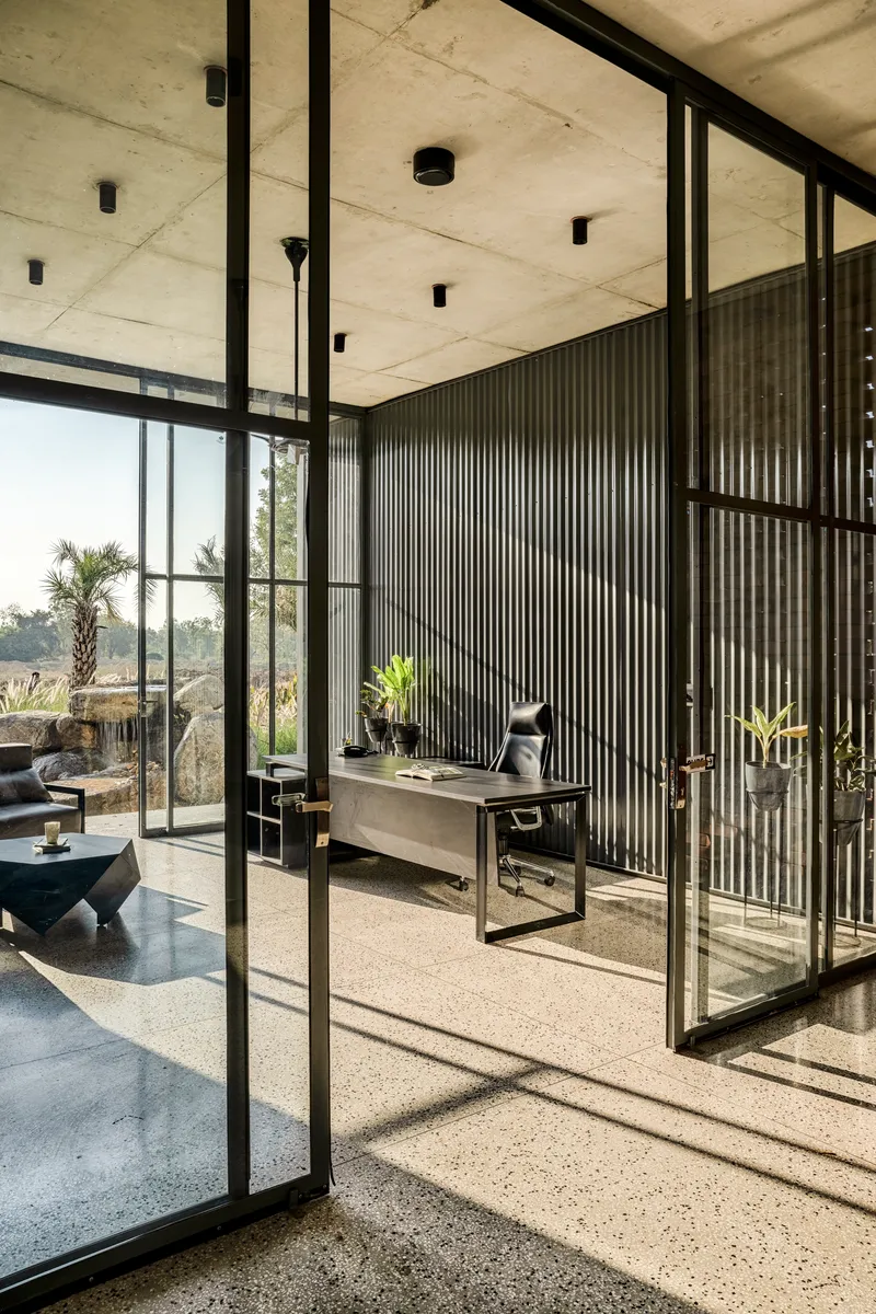 Glass-walled office with corrugated metal partition screens viewed through steel-framed sliding doors