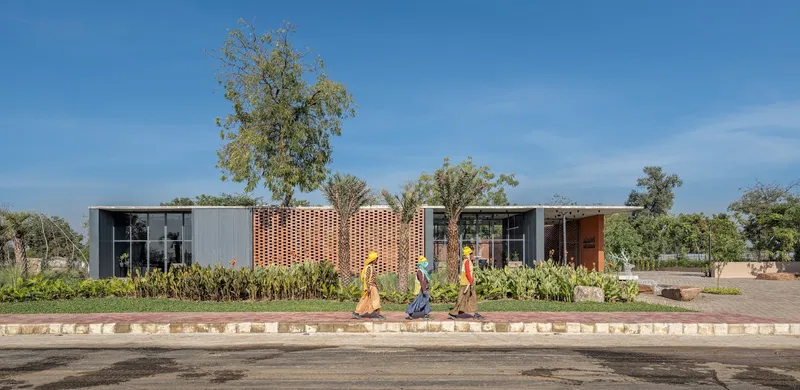Street view of the perforated brick screen facade with three pedestrians walking along the paved curb