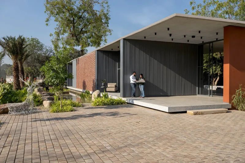 Front elevation showing perforated brick facade and corrugated metal cladding with covered terrace and brick paving