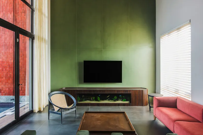 Living room with olive green wall panels, built-in aquarium, and glazed doors to terracotta courtyard