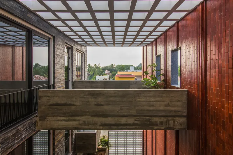 Rooftop courtyard with timber grid pergola and woven reddish-brown tile walls overlooking rooftops