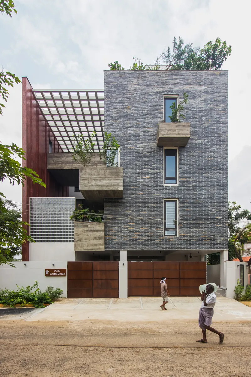 Front elevation showing staggered concrete balconies and timber grid pergola with two pedestrians passing