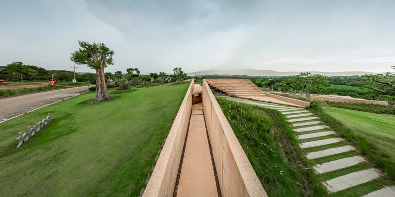 Elevated walkway flanked by green roof slopes and a concrete stepping path through grass