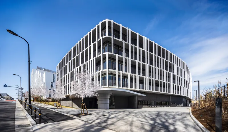 Street view of the precast concrete grid facade with a rounded corner and cantilevered base