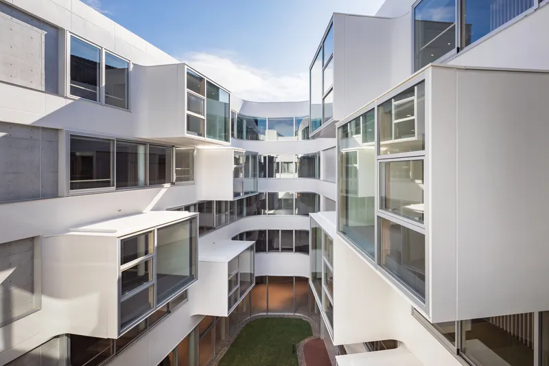 View down into the courtyard showing stacked balconies with white railings and a patch of green lawn