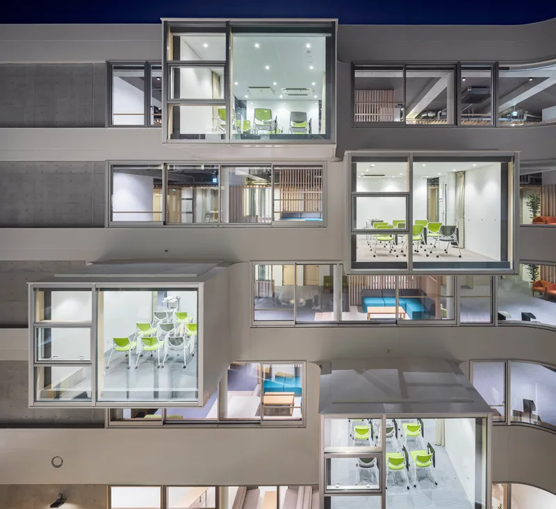 Night view of the stacked office floors with illuminated interiors visible through large windows