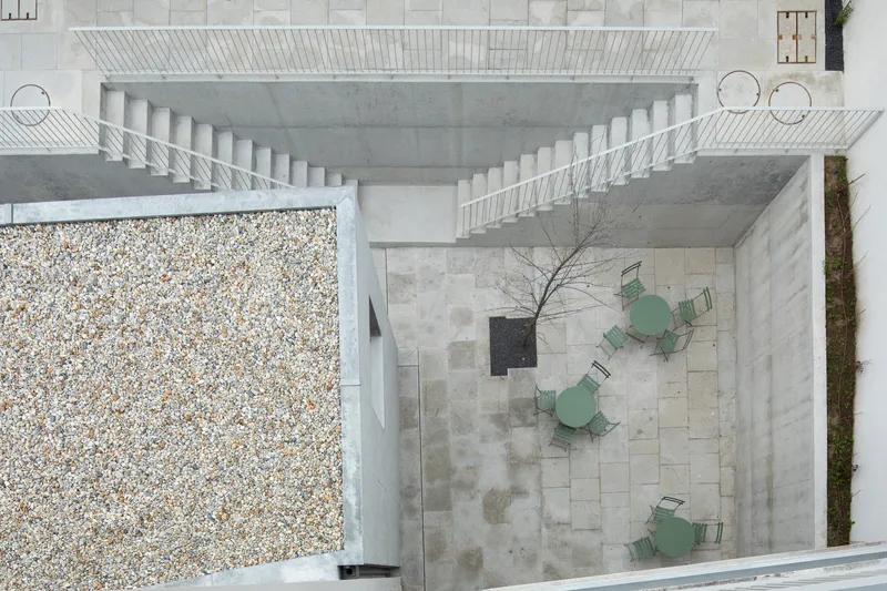 Aerial view of a stone-paved courtyard with mint green metal chairs and gravel beds