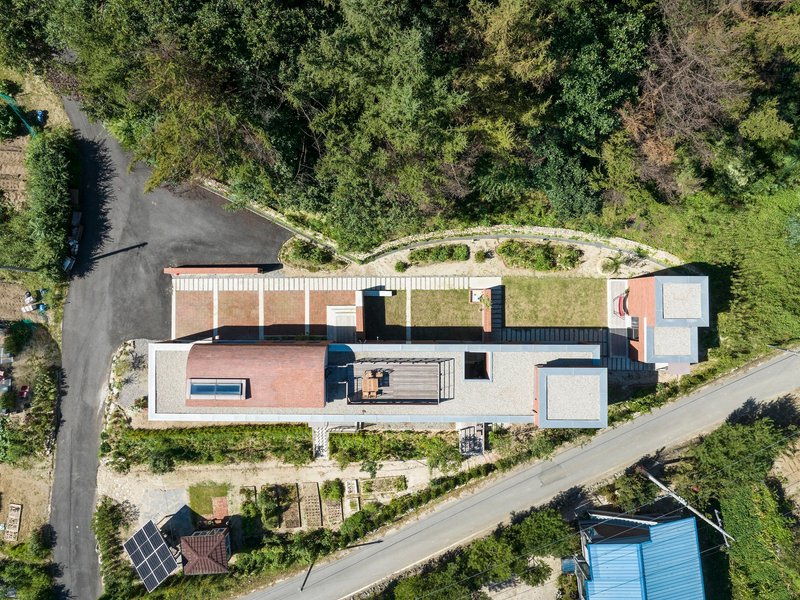 Drone view showing the curved green roof wrapping around the stepped volumes and terraces