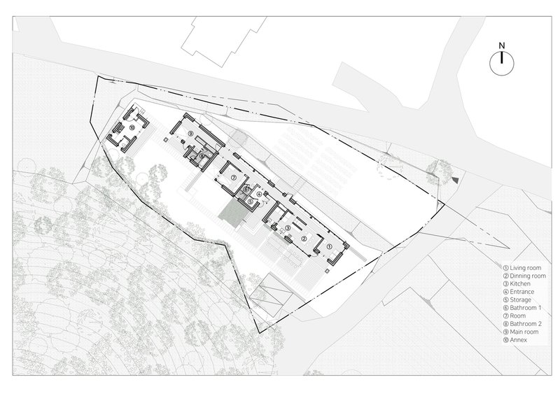 Site plan drawing showing the elongated building footprint on a triangular sloped lot with trees