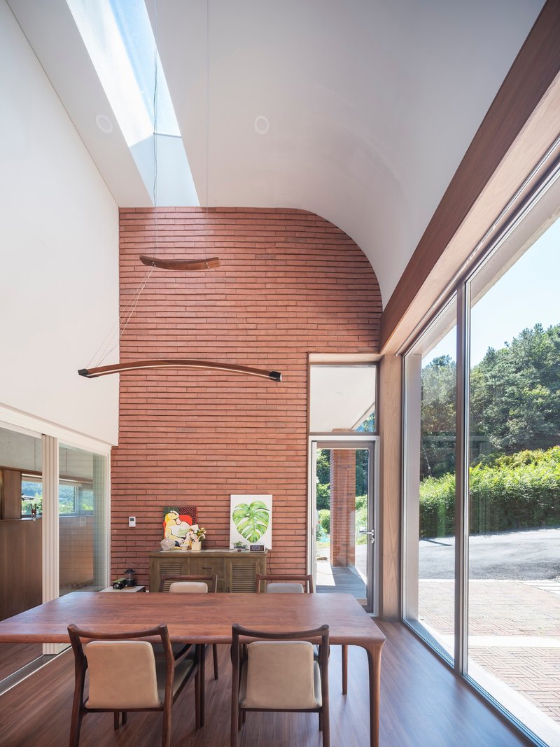 Dining area beneath a curved brick wall with skylight and sliding glass doors to the terrace