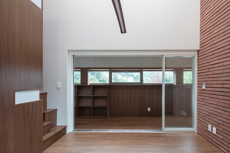 Double-height space with timber stair and glazed sliding partition to adjacent room with built-in shelving