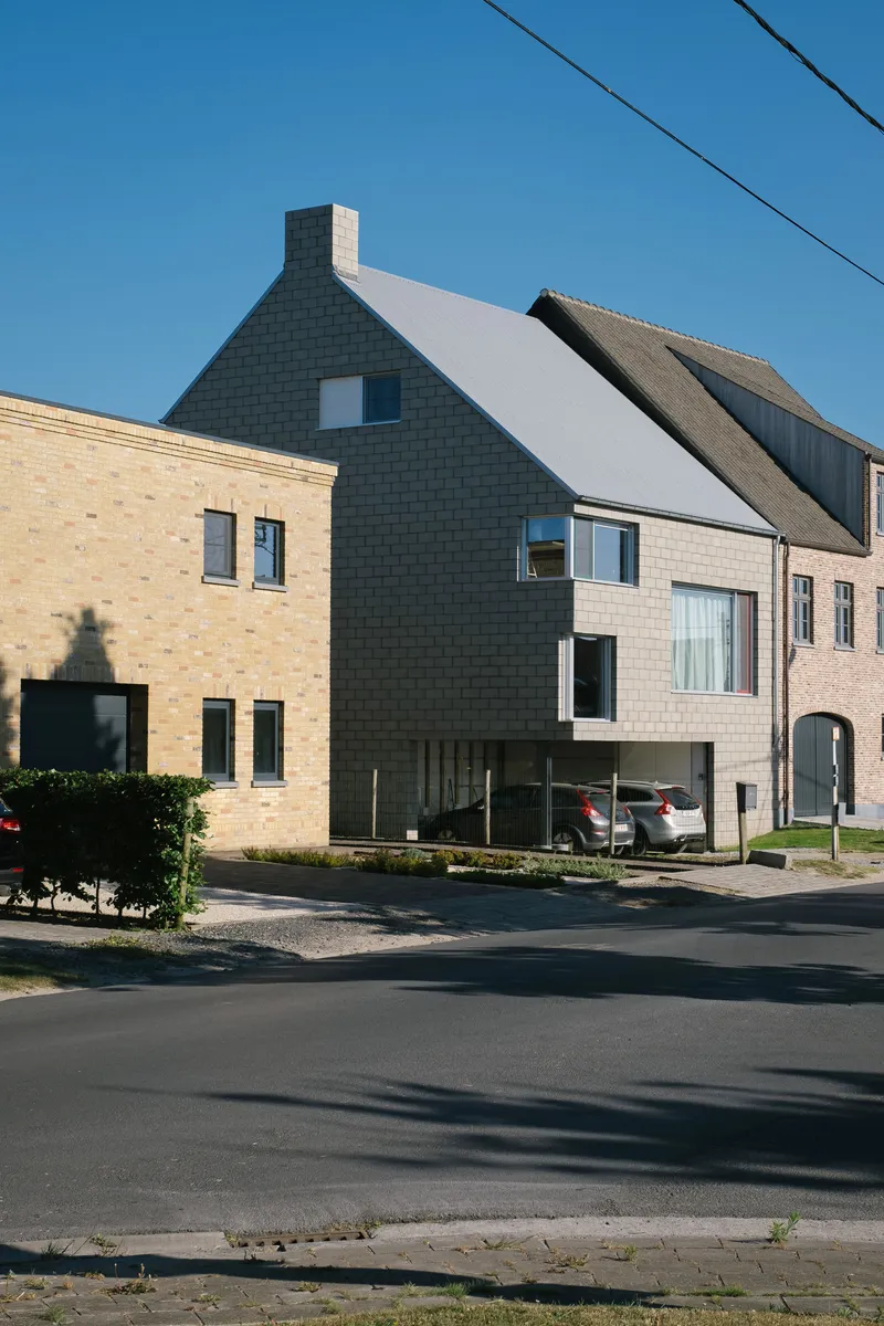 Street corner view of the dark grey masonry gable with adjacent pale brick neighbor in afternoon light