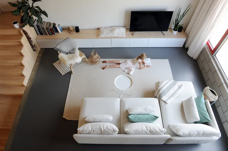 Overhead view of living room showing child playing on rug beside built-in media console