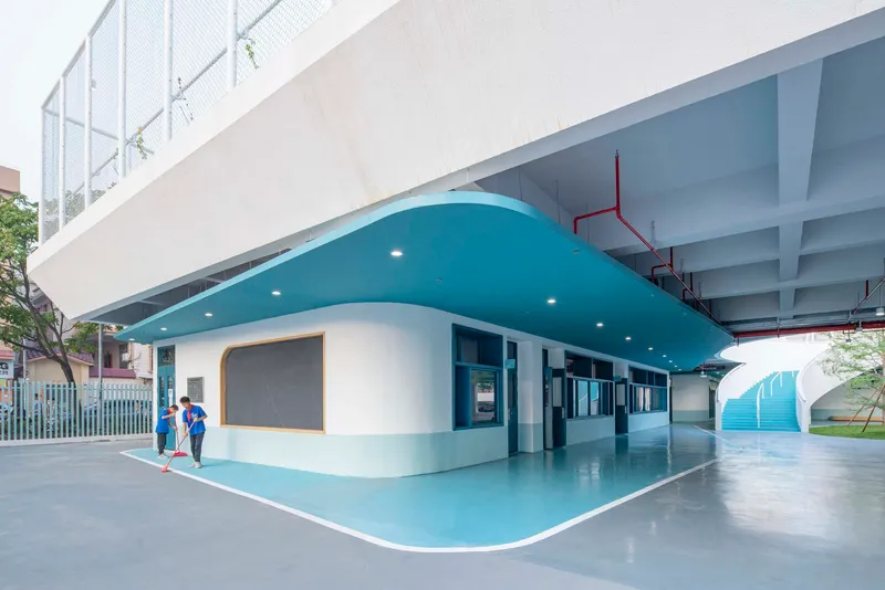 Covered ground floor corridor with curved turquoise soffit and two children walking near the entrance