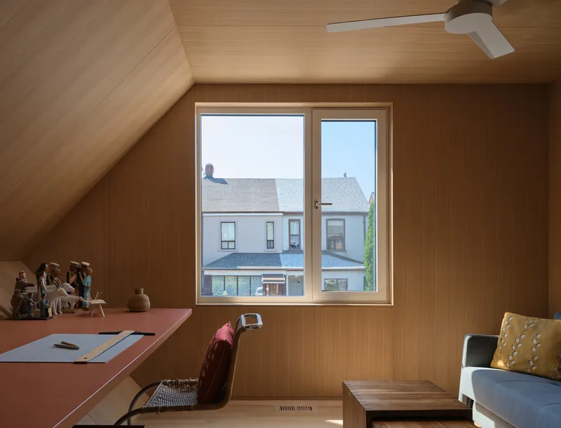 Upper-level workspace with pink desk and window overlooking neighboring rooftops